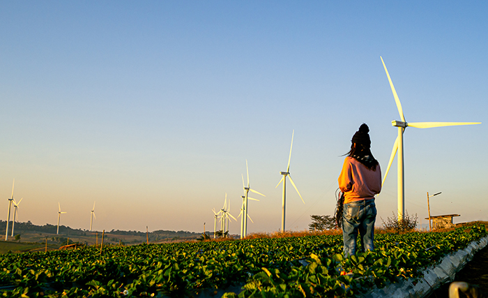 woman in field with wind turbines